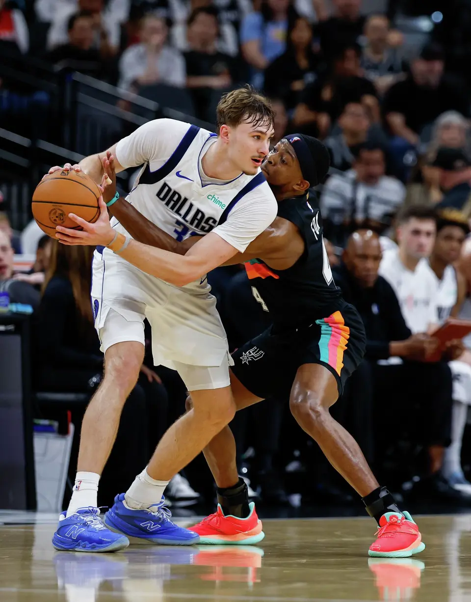 San Antonio Spurs guard De'aaron Fox (4) guards Dallas Mavericks forward Cooper Flagg (32) during an NBA game at Frost Bank Center in San Antonio, Friday, April 10, 2026.