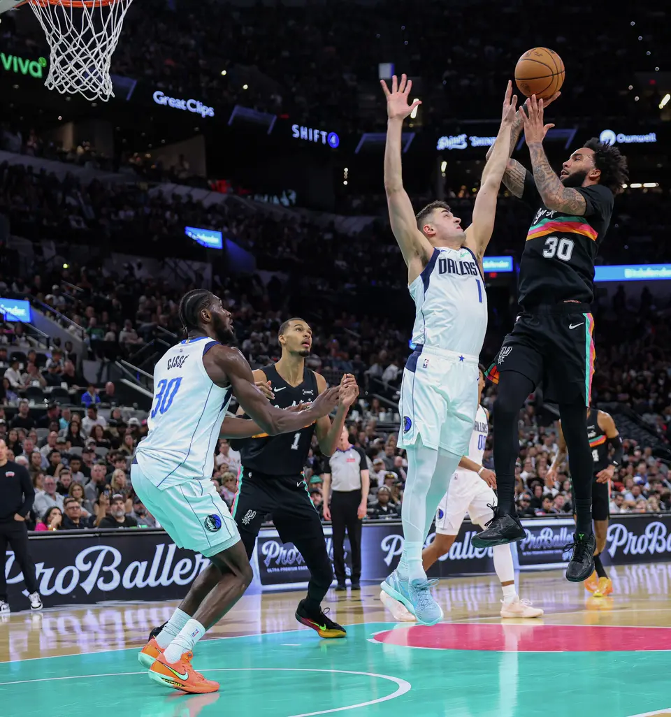 San Antonio Spurs forward Julian Champagnie (30) shoots over Dallas Mavericks guard John Poulakidas (1) during the second quarter at Frost Bank Center in San Antonio, Friday, April 10, 2026. The Spurs won 139-120.