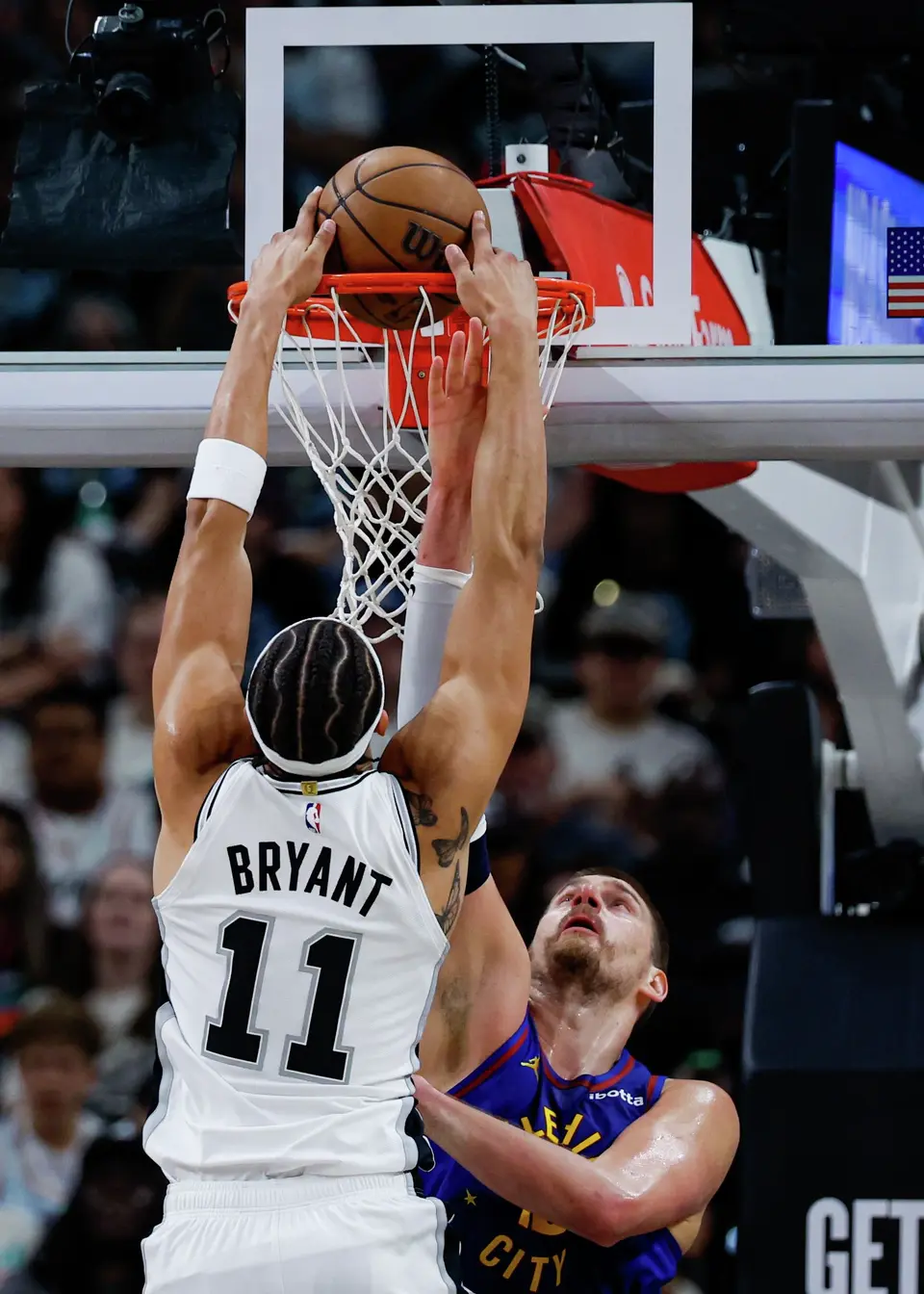 San Antonio Spurs forward Carter Bryant (11) dunks over Denver Nuggets center Nikola Jokic (15) during the first quarter at Frost Bank Center in San Antonio, Sunday, April 12, 2026.