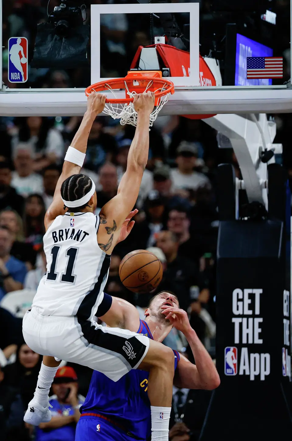 San Antonio Spurs forward Carter Bryant (11) dunks over Denver Nuggets center Nikola Jokic (15) during the first quarter at Frost Bank Center in San Antonio, Sunday, April 12, 2026.