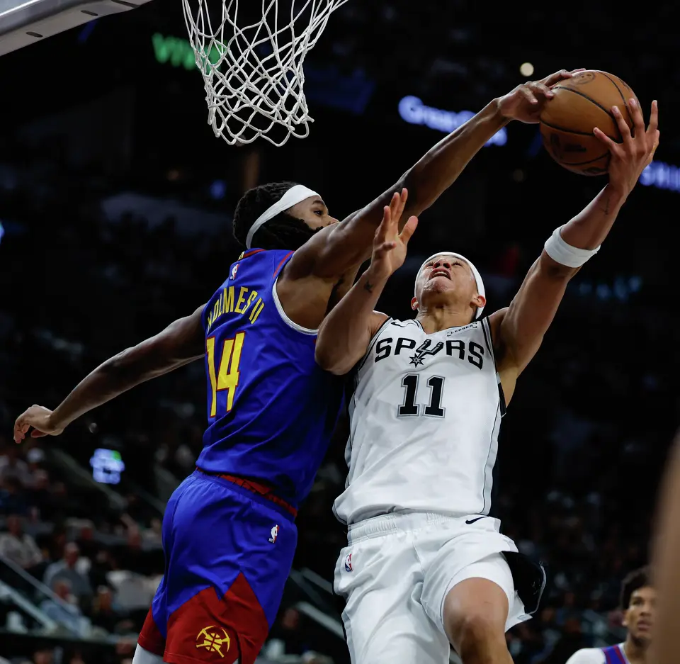 Denver Nuggets forward Daron Holmes II (14) blocks San Antonio Spurs forward Carter Bryant (11) under the net at Frost Bank Center in San Antonio, Sunday, April 12, 2026. The Spurs lost 128-118 to the Nuggets in their final regular-season game.