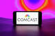 In this photo illustration, the Comcast logo is seen displayed on a mobile phone screen.