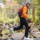 Woman hiking across rocks in a stream in the woods with The Jackery Explorer 300.