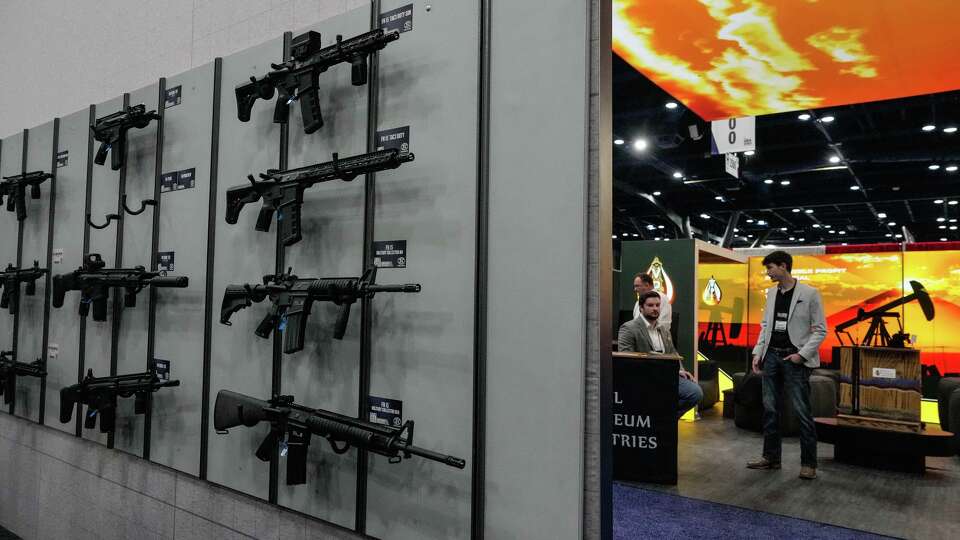 Attendees walk the convention floor and browse firearms and merchandise during the National Rifle Association convention at the George R. Brown Convention Center in Houston, Friday, April 17, 2026.