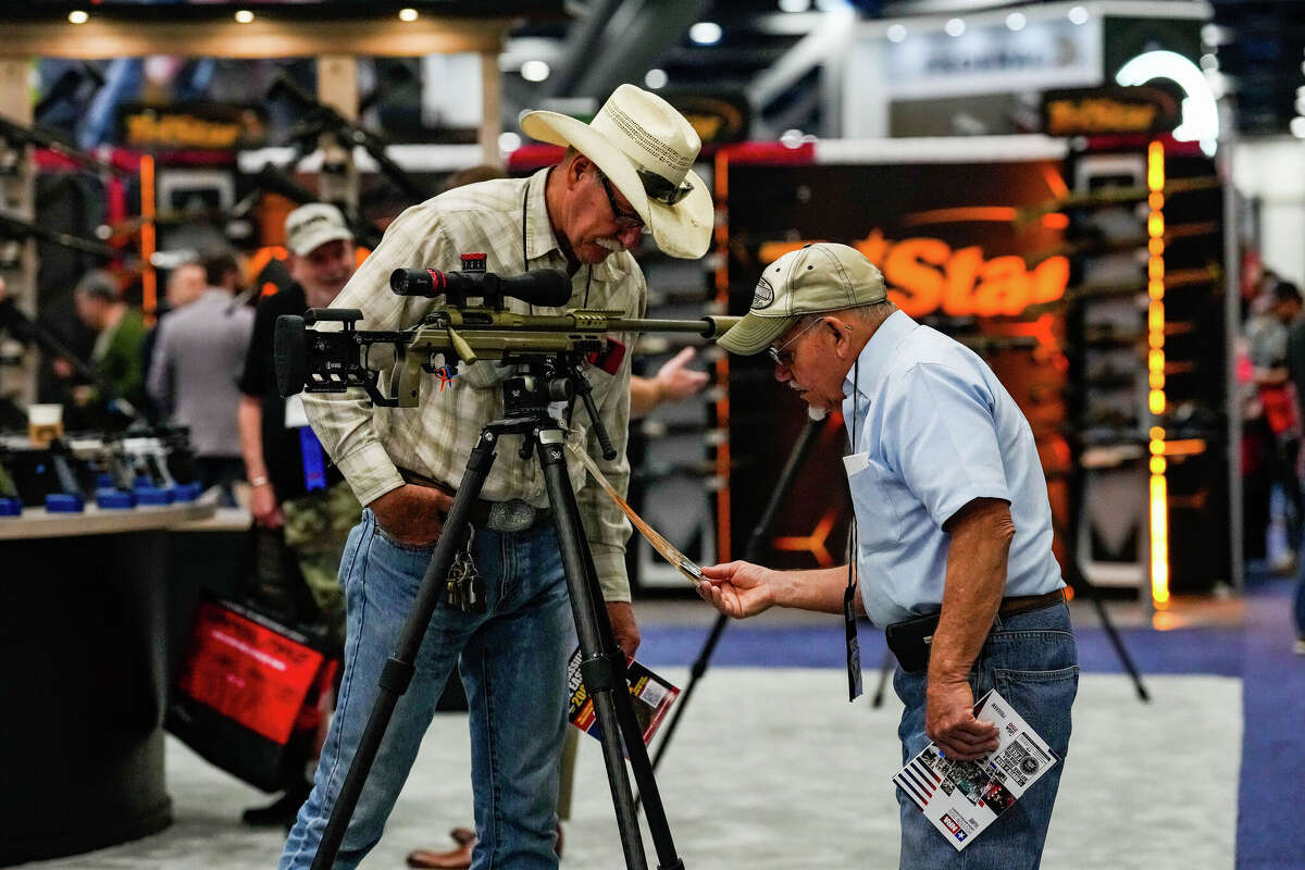 Attendees walk the convention floor and browse firearms and merchandise during the National Rifle Association convention at the George R. Brown Convention Center in Houston, Friday, April 17, 2026.
