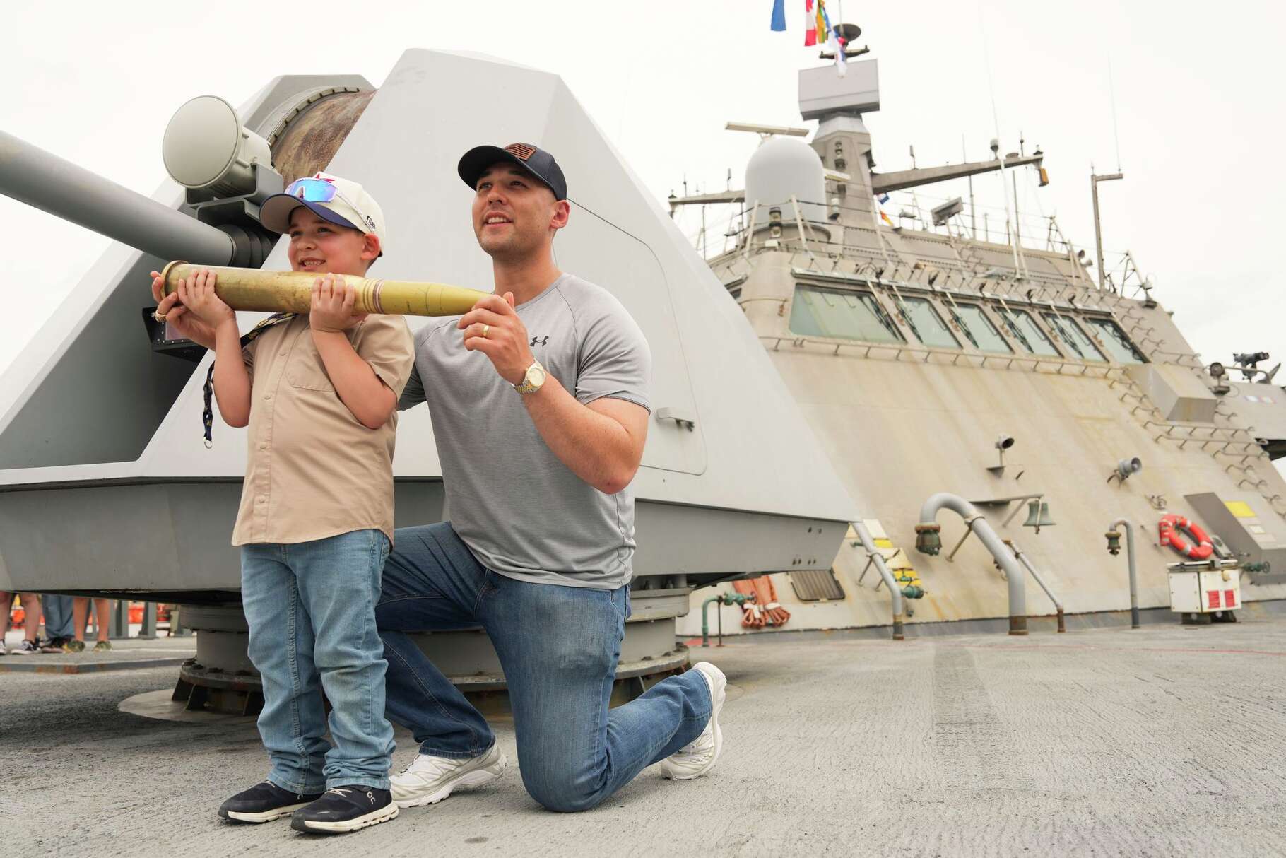 Joseph Barrera and his son, Sebastian, pose for a photo holding a 57mm artillery round aboard the USS St. Louis, a Freedom-class littoral combat ship, during Fleet Week, Saturday, April 178, 2026, in Houston.