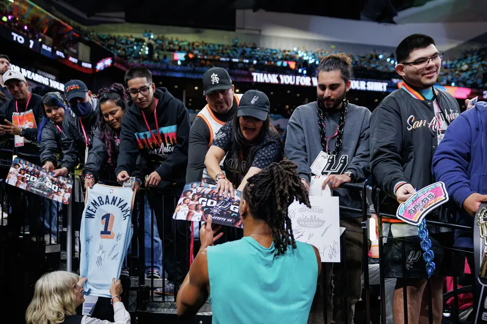San Antonio Spurs guard Devin Vassell, center, signs autographs for fans before the start of Game 1 of a first-round NBA playoff series against the Portland Trail Blazers at Frost Bank Center, Sunday, April 19, 2026, in San Antonio.