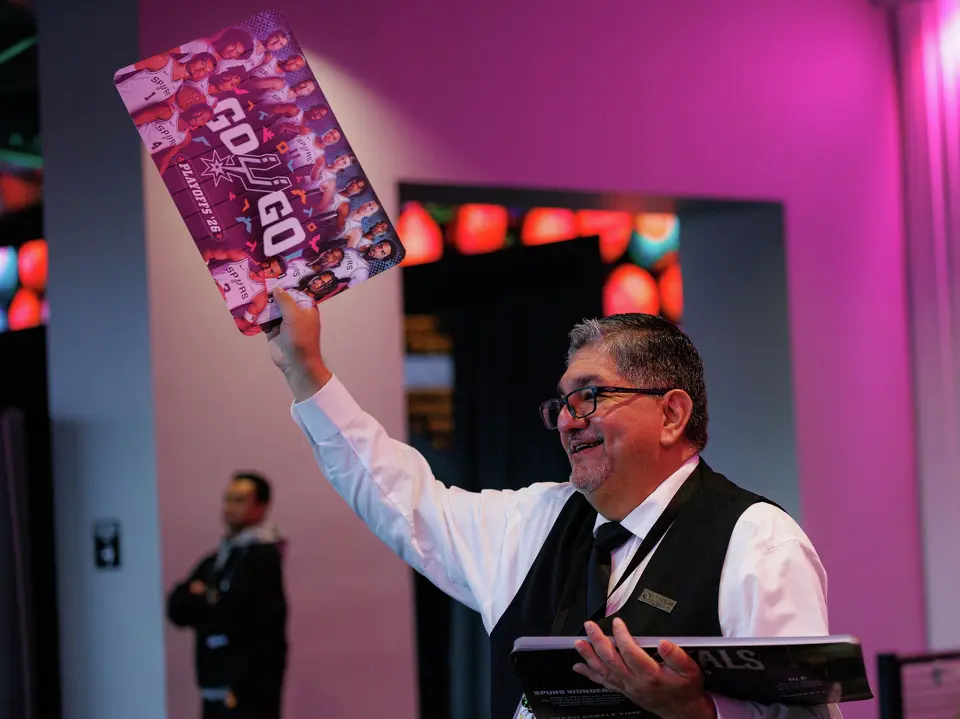 Jerry Casarez hands out noise makers to San Antonio Spurs fans as they make their way into Frost Bank Center before the start of Game 1 of a first-round NBA playoff series against the Portland Trail Blazers on Sunday, April 19, 2026, in San Antonio.