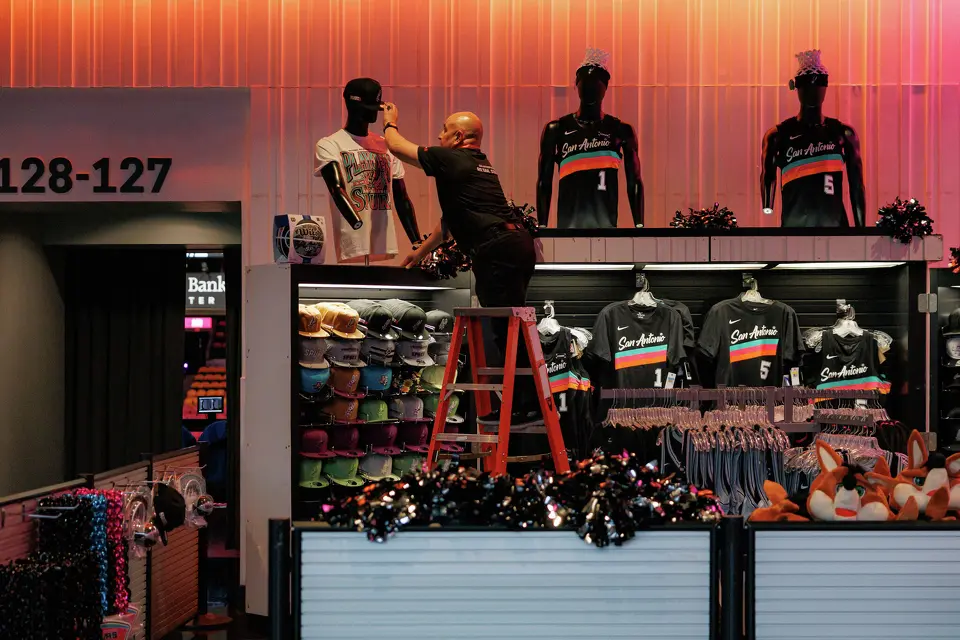 A retail worker adjusts merchandize at a fan shop outside of Section 127-128 at Frost Bank Center, Sunday, April 19, 2026, in San Antonio, before the start of Game 1 of a first-round NBA playoff series between the San Antonio Spurs and the Portland Trail Blazers.