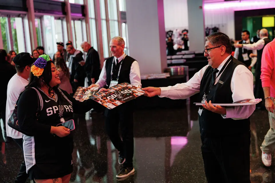 Jerry Casarez, right, hands out noise makers to San Antonio Spurs fans as they make their way into Frost Bank Center before the start of Game 1 of a first-round NBA playoff series against the Portland Trail Blazers on Sunday, April 19, 2026, in San Antonio.
