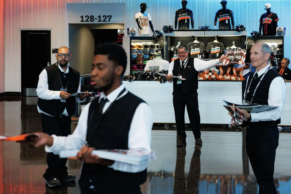Frost Bank employees hand out noise makers to San Antonio Spurs fans as they make their way into the arena before the start of Game 1 of a first-round NBA playoff series against the Portland Trail Blazers on Sunday, April 19, 2026, in San Antonio.