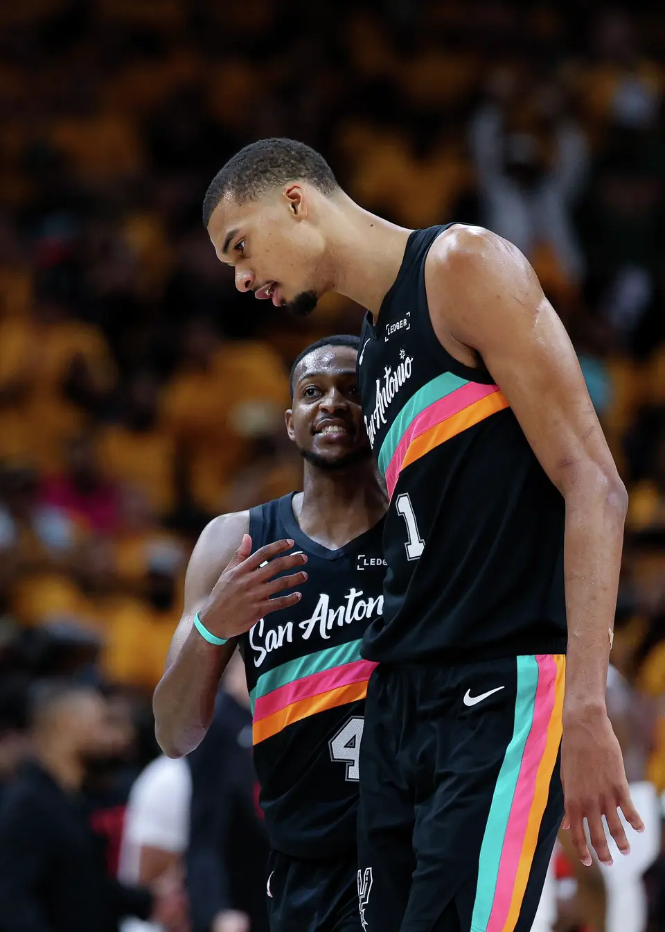 San Antonio Spurs guard De'aaron Fox (4) and forward Victor Wembanyama (1) talk during a timeout in the second half of Game 1 of a first-round NBA playoff series against the Portland Trail Blazers at Frost Bank Center, Sunday, April 19, 2026, in San Antonio. The Spurs won 111-98.