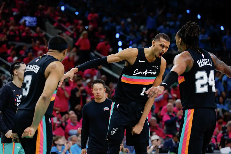 San Antonio Spurs forward Victor Wembanyama (1) slaps hands with San Antonio Spurs guard Devin Vassell (24) during a timeout in the second half of Game 1 of a first-round NBA playoff series against the Portland Trail Blazers at Frost Bank Center, Sunday, April 19, 2026, in San Antonio. The Spurs won 111-98.