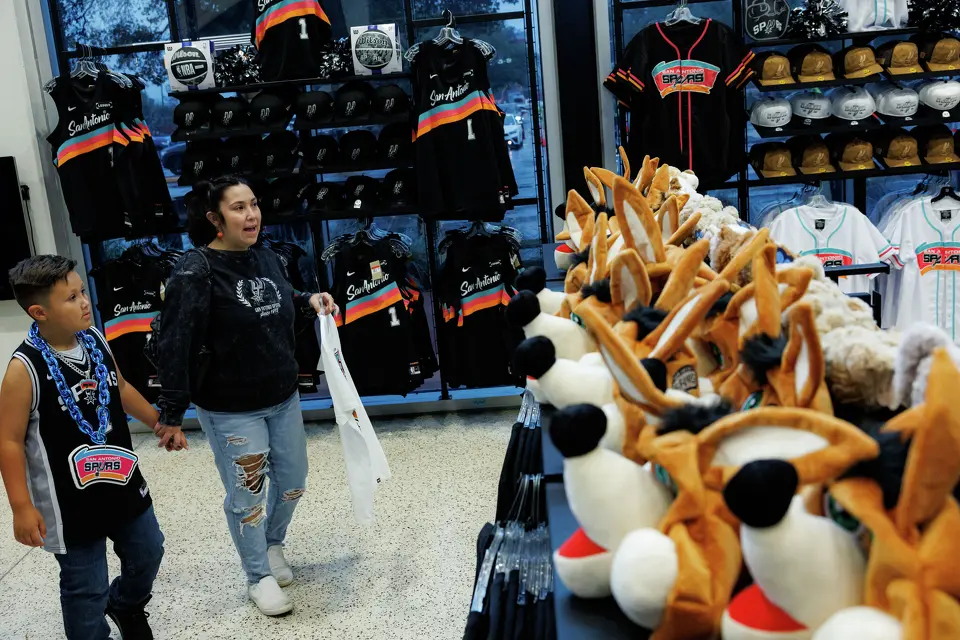 Kassy Gandy from Edna and her 7-year-old son Jaxon walk through a fan shop before game 2 of a first-round NBA playoff series between the San Antonio Spurs and the Portland Trail Blazers at Frost Bank Center in San Antonio, Tuesday, April 21, 2026.