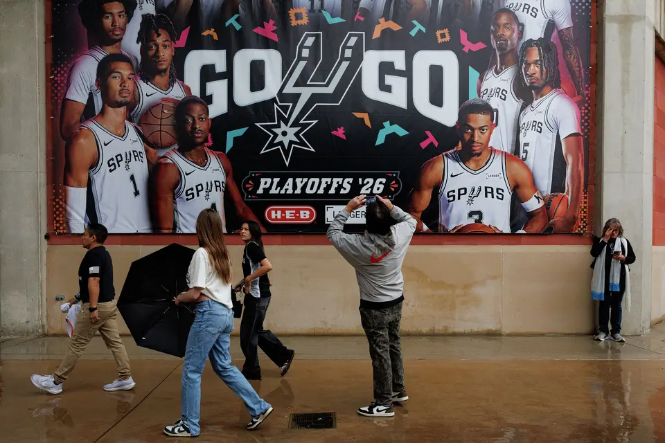 People enter Frost Bank Center in the rain before Game 2 of a first-round NBA playoff series between the San Antonio Spurs and the Portland Trail Blazers in San Antonio, Tuesday, April 21, 2026.