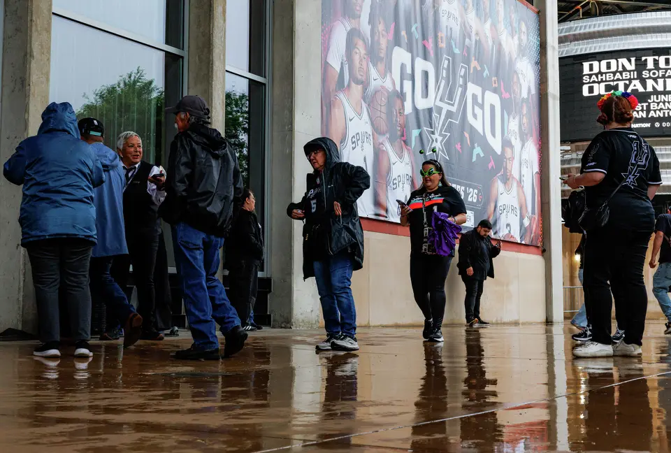 People enter Frost Bank Center in the rain before Game 2 of a first-round NBA playoff series between the San Antonio Spurs and the Portland Trail Blazers in San Antonio, Tuesday, April 21, 2026.