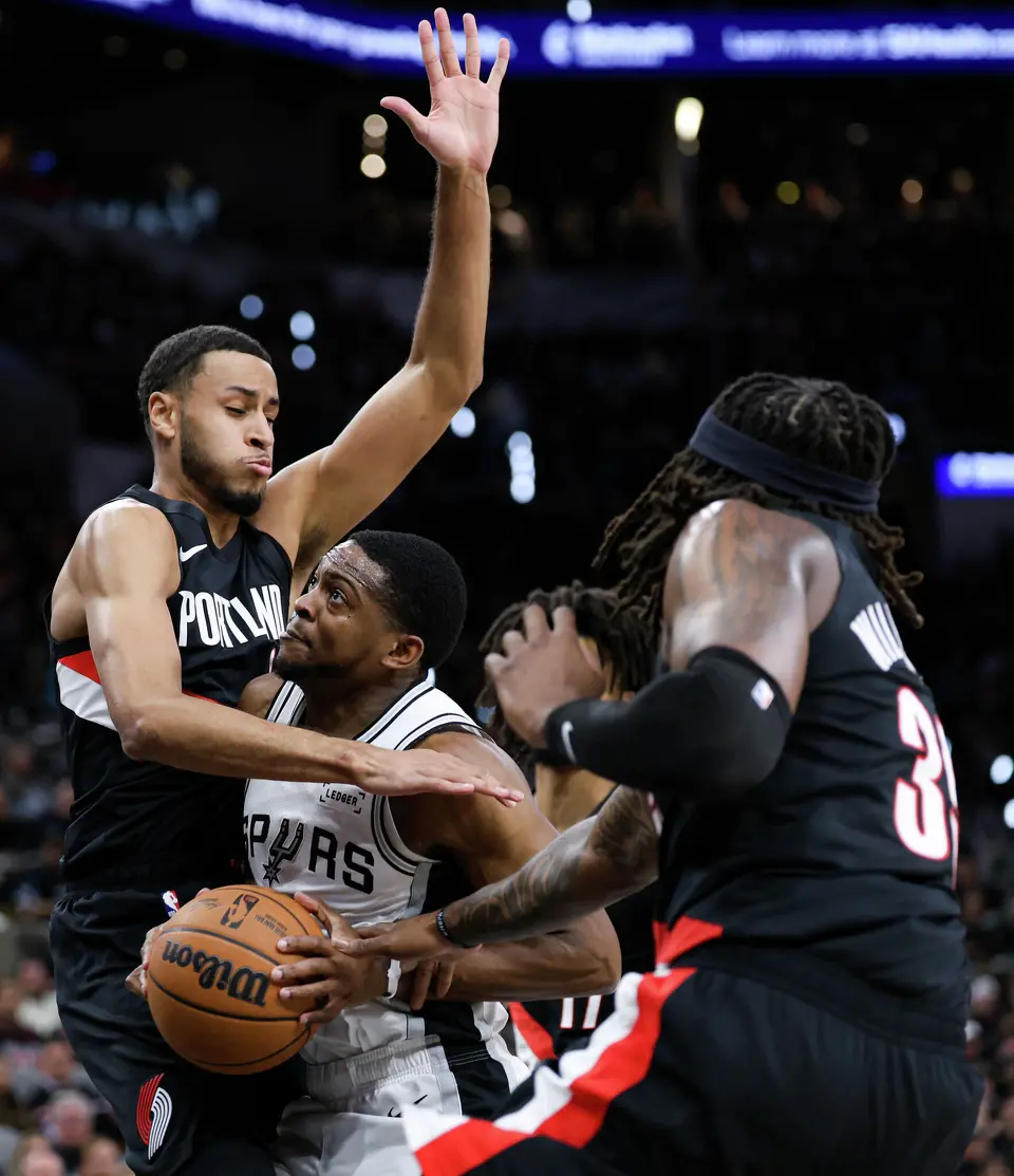 San Antonio Spurs guard De'aaron Fox (4) drives through Portland Trail Blazers forward Kris Murray (24) and center Robert Williams III (35) during the first half of Game 2 of a first-round NBA playoff series at Frost Bank Center in San Antonio, Tuesday, April 21, 2026.