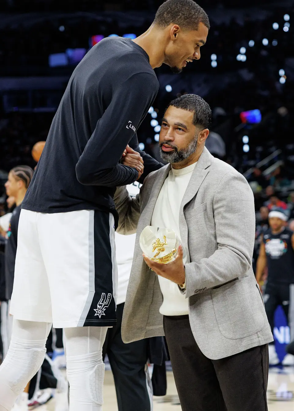 San Antonio Spurs player Victor Wembanyama embraces Brian Wright, general manager of the Spurs, before receiving his NBA Defensive Player of the Year trophy before Game 2 of a first-round NBA playoffs basketball series against the Portland Trail Blazers in San Antonio, Tuesday, April 21, 2026