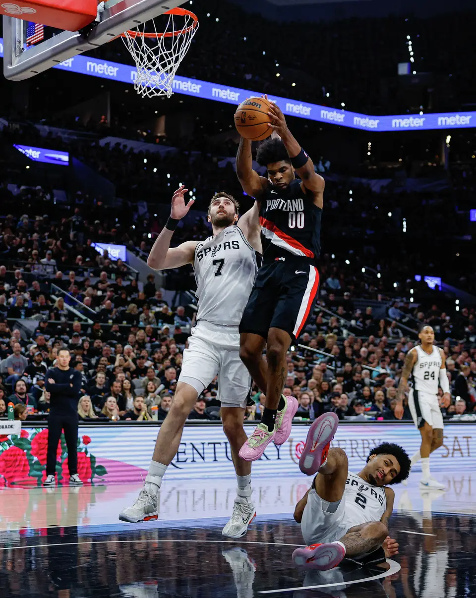 Portland Trail Blazers guard Scoot Henderson (00) rebounds the ball as San Antonio Spurs guard Dylan Harper (2) falls the ground after attempting a shot during the first half of Game 2 of a first-round NBA playoff series at Frost Bank Center in San Antonio, Tuesday, April 21, 2026. The Spurs lost 106-103, tying the series 1-1.