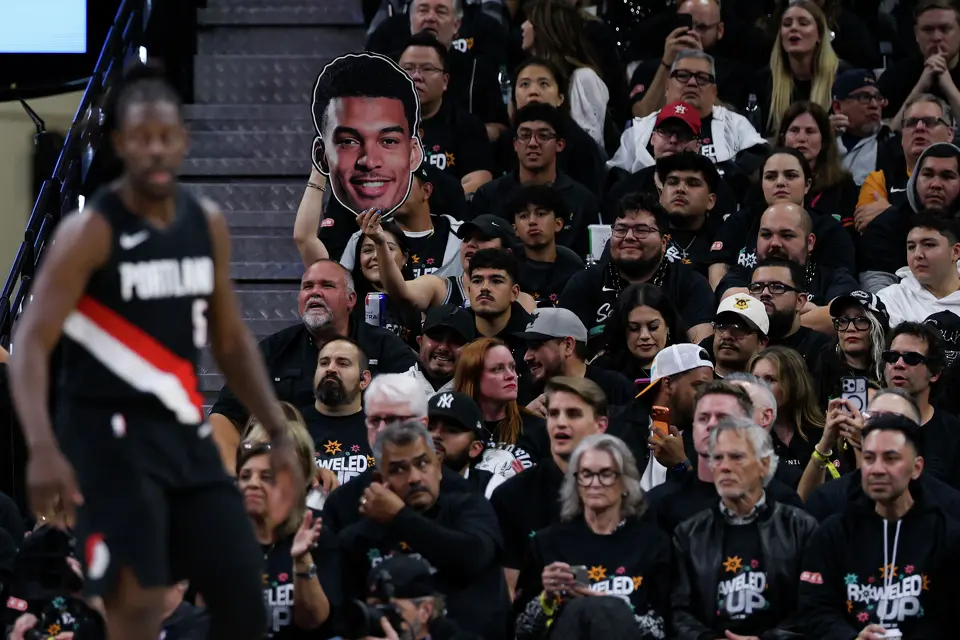 A San Antonio Spurs fan holds up a large photo of Spurs forward Victor Wembanyama, who was injured in the first half and left the game early, during Game 2 of a first-round NBA playoff series against the Portland Trail Blazers at Frost Bank Center in San Antonio, Tuesday, April 21, 2026. The Spurs lost 106-103, tying the series 1-1.
