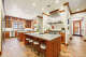 The gourmet kitchen features dual islands and exposed brick flooring.