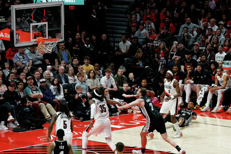 San Antonio Spurs guard Stephon Castle (5), bottom right, falls to the ground as he makes a 3-pointer during the fourth quarter of Game 3 of a first-round NBA playoff series against the Portland Trail Blazers at Moda Center in Portland, Saturday, April 25, 2026. The Spurs defeated the Trail Blazers 120-108 to lead the series 2-1.