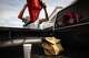 Scott Wheeler opens his DoorDash food bag and secures a delivery order in the bed of his truck in Dallas, March 31, 2026. The drink rides in his truck cabin’s cupholder.
