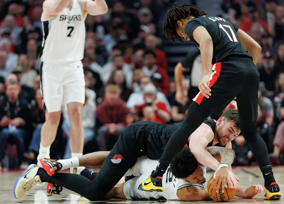 Portland Trail Blazers center Donovan Clingan (23) and San Antonio Spurs guard Dylan Harper (2) tangle on the ground as they fight for the ball during the first quarter of Game 4 of a first-round NBA playoff series at Moda Center on Sunday, April 26, 2026.
