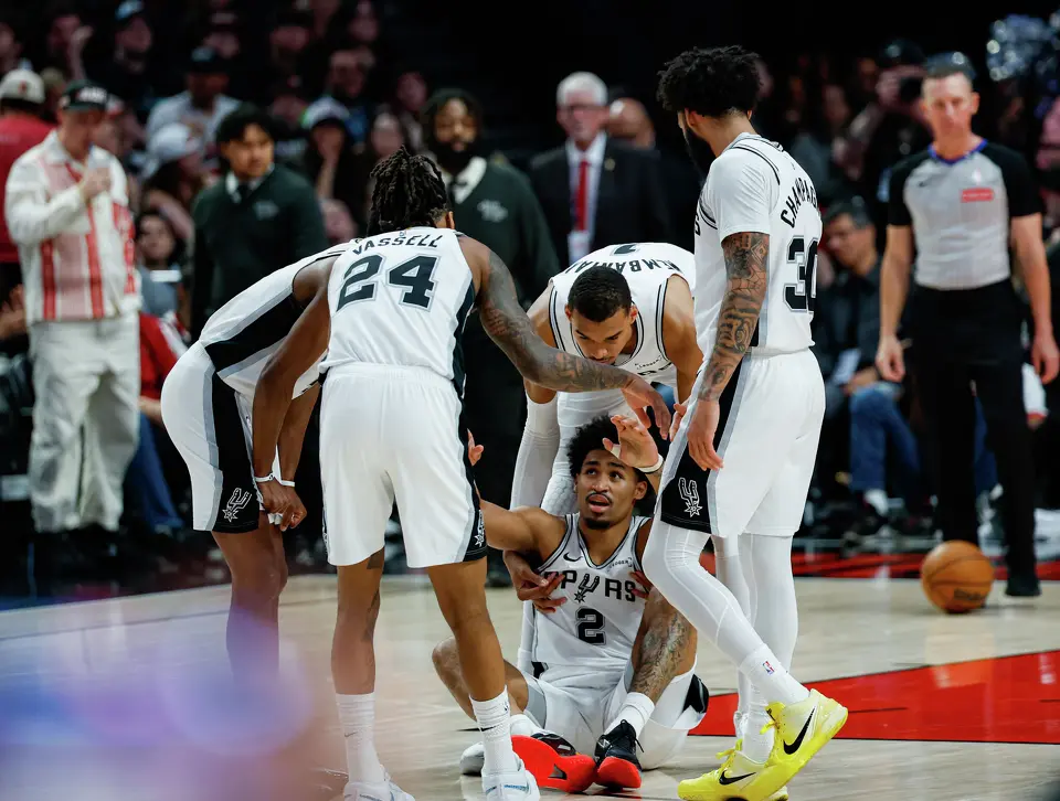 San Antonio Spurs guard Dylan Harper (2) is helped up by his teammates after falling while playing defense against the Portland Trail Blazers during the second quarter of Game 4 of a first-round NBA playoff series at Moda Center on Sunday, April 26, 2026.