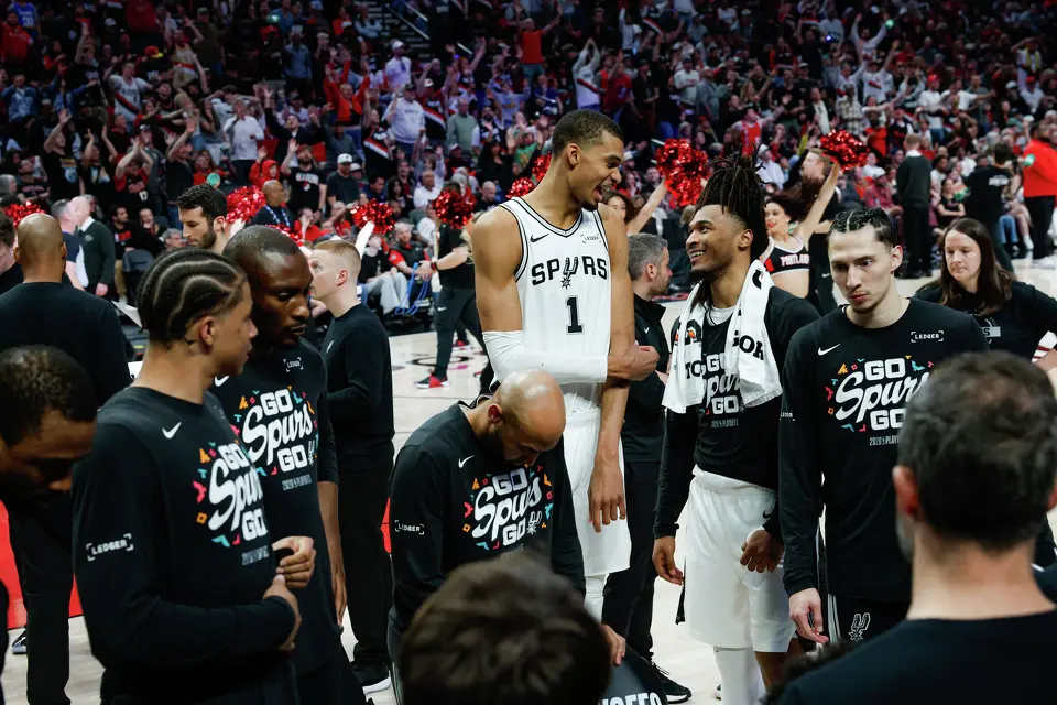 San Antonio Spurs forward Victor Wembanyama, center, is all smiles as he talks to his teammate San Antonio Spurs guard Stephon Castle (5) during a fourth quarter timeout in Game 4 of a first-round NBA playoff series at Moda Center on Sunday, April 26, 2026. The Spurs won 114-93, leading the series 3-1.