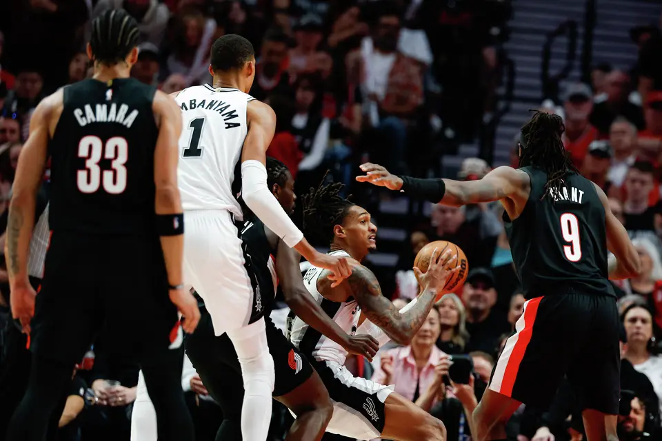 San Antonio Spurs guard Devin Vassell, center, is guarded by Portland Trail Blazers guard Jrue Holiday (5) as he goes up for a jump shot during the third quarter of Game 4 of a first-round NBA playoff series at Moda Center on Sunday, April 26, 2026.