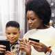 Mother with credit card and son with cell phone sitting on couch. ICCU youth accounts have free automatic parent transfers.