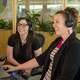 Two smiling women with headphones seated at a computer. May 2 is National Life Insurance Day.