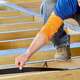Man applying Trex® Protect joist flashing tape to his deck.