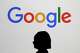 FILE - A woman walks by a giant screen displaying the Google logo at an event at the Paris Google Lab on the sidelines of the AI Action Summit in Paris, Feb. 9, 2025.