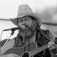 FILE - David Allan Coe, sporting Willie Nelson braids, performs at the Willie Nelson July 4th Picnic, on July 4, 1983 at Atlanta International Raceway in Hampton, Ga.