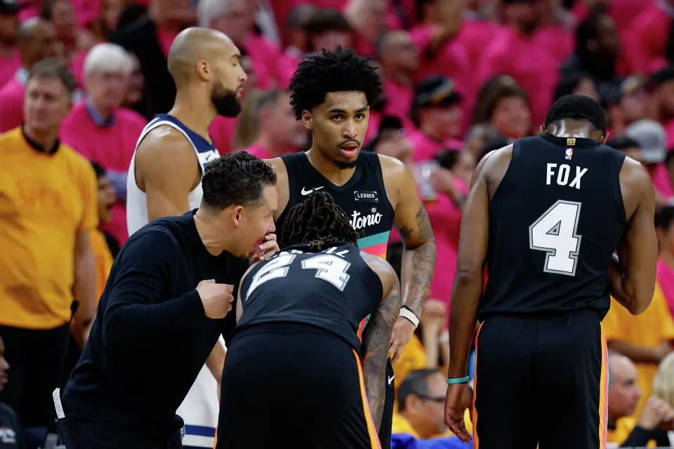 San Antonio Spurs head coach Mitch Johnson, from left, talks to guard Devin Vassell (24), guard Dylan Harper (2) and guard De'aaron Fox (4) during the fourth quarter of Game 1 of the Western Conference semifinals against the Minnesota Timberwolves at Frost Bank Center in San Antonio, Monday, May 4, 2026. The Spurs could be without both Harper and Fox in Game 3 of the Western Conference finals against the Oklahoma City Thunder on Friday. Fox has missed the first two games of the series with a right ankle sprain, while Harper left Game 2 early and didn't return. Both are listed as questionable.