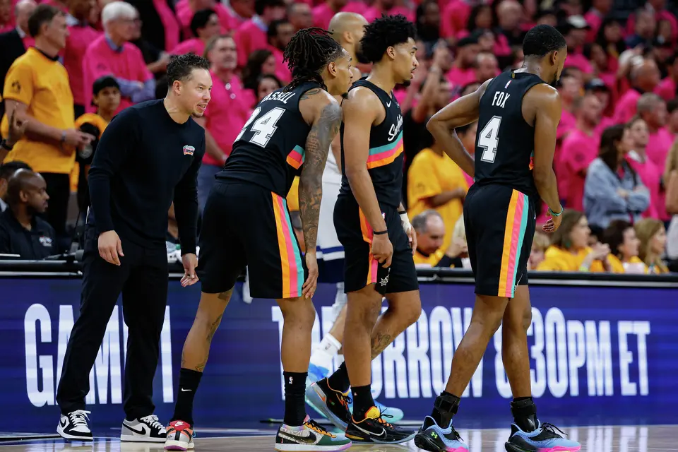 San Antonio Spurs head coach Mitch Johnson, from left, talks to guard Devin Vassell (24), guard Dylan Harper (2) and guard De'aaron Fox (4) during the fourth quarter of Game 1 of the Western Conference semifinals against the Minnesota Timberwolves at Frost Bank Center in San Antonio, Monday, May 4, 2026. The Spurs fell 104-102 to the Timberwolves.