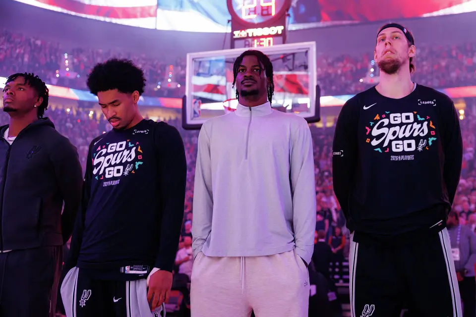 San Antonio Spurs forward Harrison Ingram, from left, guard Dylan Harper, forward Emanuel Miller and forward Kelly Olynyk stand for the National Anthem before the start of Game 3 of a first-round NBA playoff series against the Portland Trail Blazers at Moda Center in Portland, Friday, April 24, 2026.