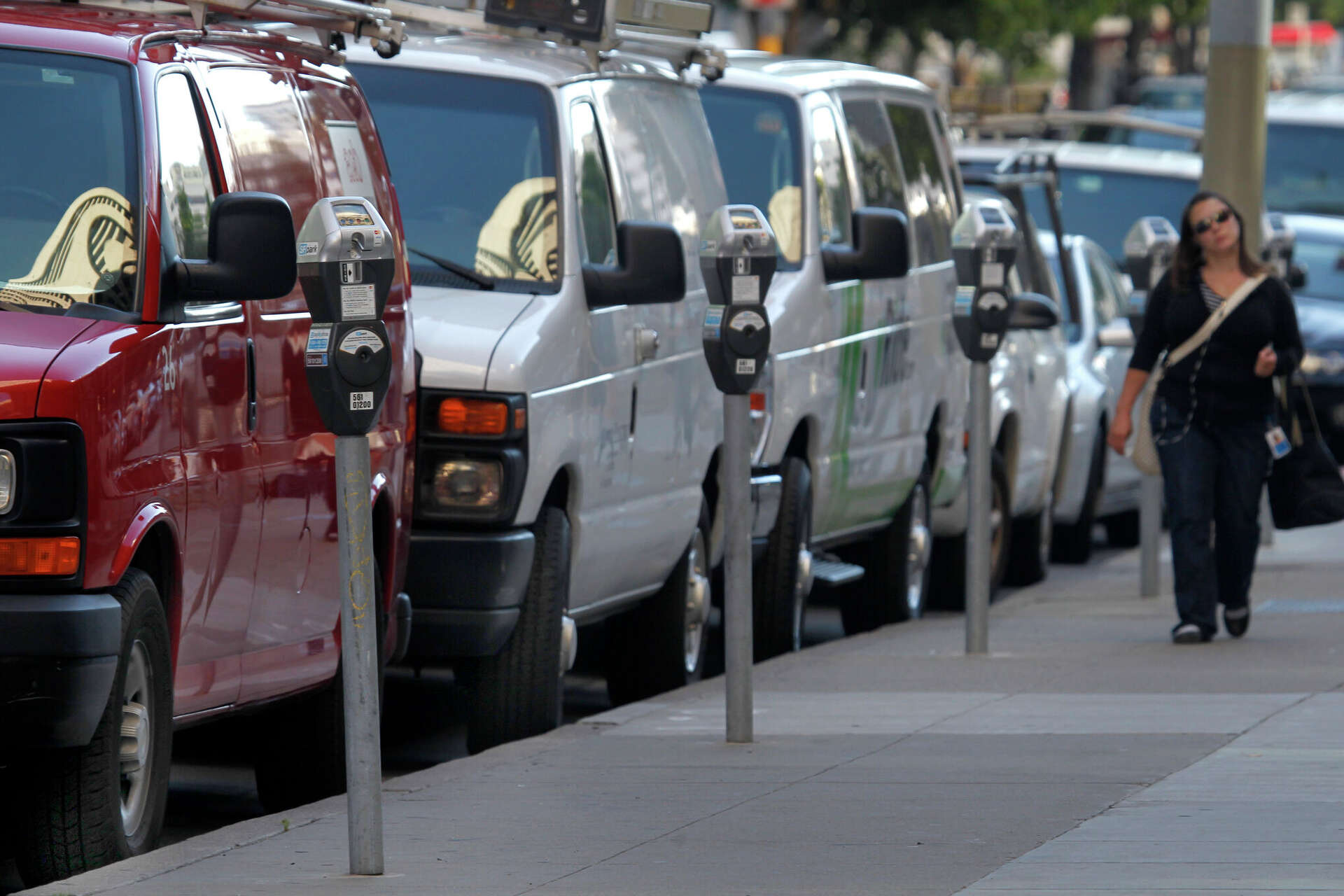 Cars and vans are parked in metered spaces on Main Street in San Francisco in 2013. The city is updating its parking app to make the practice easier, including 