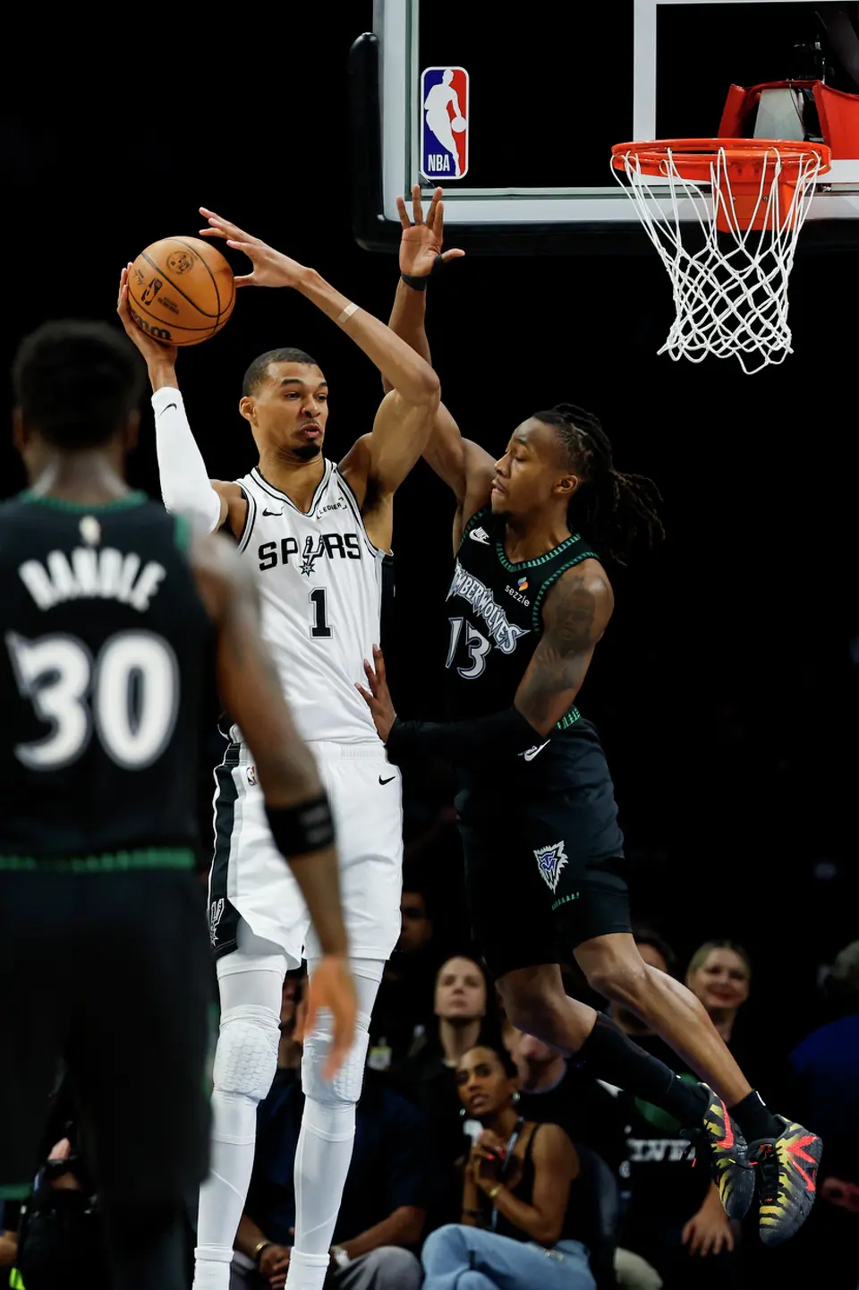 San Antonio Spurs forward Victor Wembanyama (1) looks to make a pass while guarded by Minnesota Timberwolves guard Ayo Dosunmu (13) during the first half of Game 3 of the Western Conference semifinals at Target Center in Minneapolis, Friday, May 8, 2026.