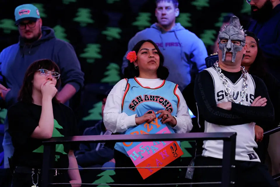 San Antonio Spurs fans Brandy Martinez, center, and Martin Aquino, right, watch the team warm up before Game 4 of the Western Conference semifinals against the Minnesota Timberwolves at Target Center in Minneapolis on Sunday, May 10, 2026.