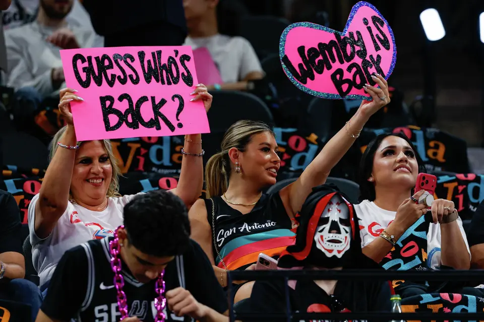 Kelly Cabrera, left, and Karly DeLeon hold signs reading “Guess who’s back?” and “Wemby is back” before Game 5 of the Western Conference semifinals between the San Antonio Spurs and the Minnesota Timberwolves at Frost Bank Center in San Antonio on Tuesday, May 12, 2026. San Antonio Spurs forward Victor Wembanyama was ejected early in the second quarter of Game 4, but will return with no further penalties.
