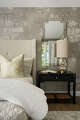 A statement mirror reflects the natural light streaming in this bedroom.