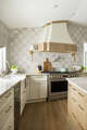 Textured detail draws the eye to the range hood. The kitchen is filled with cozy neutrals.