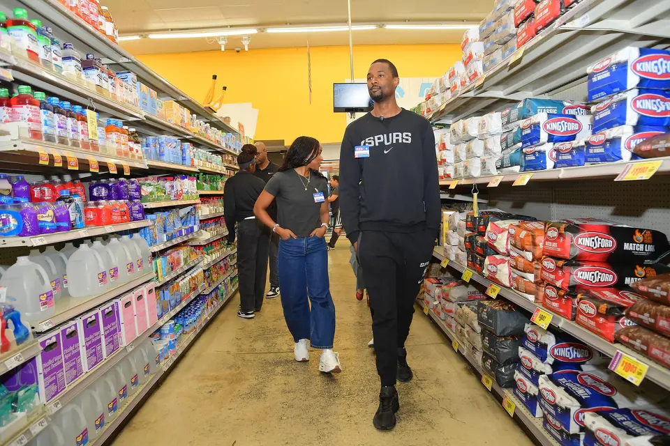 San Antonio Spurs forward Harrison Barnes, front, and his wife Brittany Barnes walk through H-E-B as they host a holiday shopping spree for families in San Antonio, Texas, on November 20, 2025