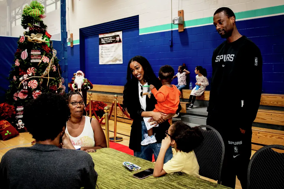 Brittany Barnes, center, and her husband San Antonio Spurs forward Harrison Barnes greet families during a Christmas community event at the Davis-Scott Family YMCA in San Antonio, Texas, on Friday, December 26, 2025.
