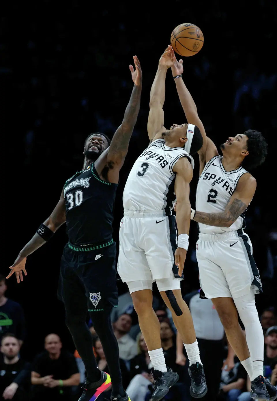 Minnesota Timberwolves forward Julius Randle (30) fights with San Antonio Spurs forward Keldon Johnson (3) and Spurs guard Dylan Harper (2) for a rebound during the first half of Game 6 of the Western Conference semifinals at Target Center in Minneapolis, Friday, May 15, 2026.