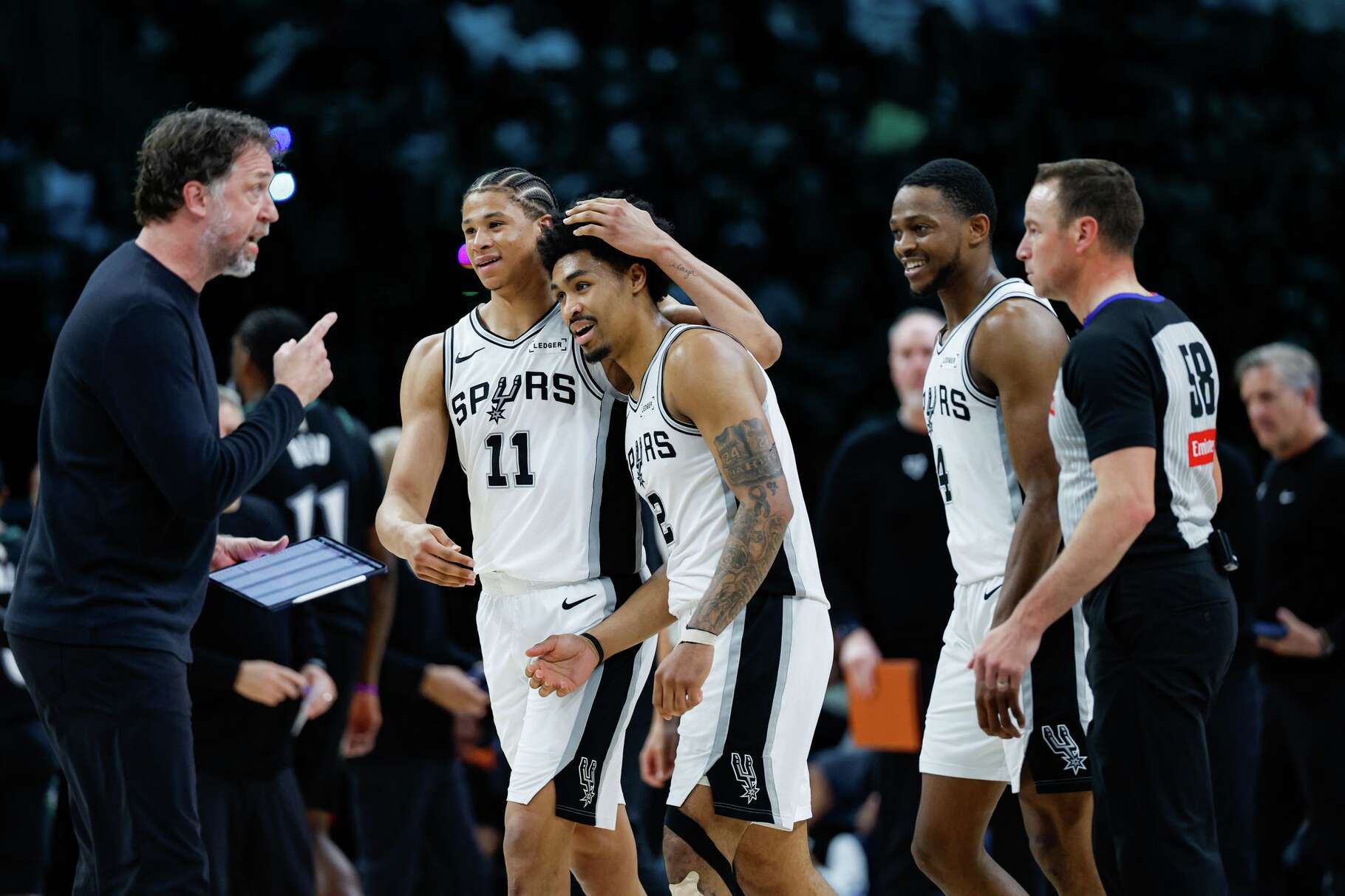 San Antonio Spurs’ Carter Bryant (11) embraces fellow rookie Dylan Harper (2) as they walk to the bench with veteran guard De'Aaron Fox (4) during a timeout in the fourth quarter of Game 6 of the Western Conference semifinals against the Minnesota Timberwolves at Target Center in Minneapolis, Friday, May 15, 2026. The Spurs defeated the Timberwolves 139-109 and will advance to the Western Conference Finals to face the Oklahoma City Thunder.