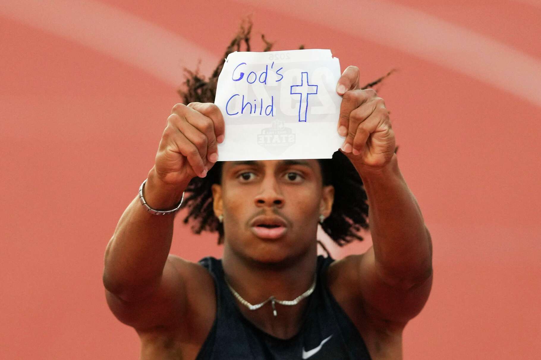 Blake Hamilton of Katy Tompkins holds up the other side of his bib number to reveal ‘God’s Child’ written on the back after winning the Class 6A boys 200-meter dash during the UIL State Track and Field Championships in Austin, Saturday, May 16, 2026.